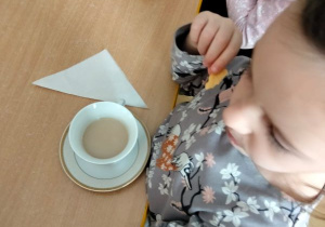 Dzieci siedzą przy stole i piją herbatę z filiżanek
