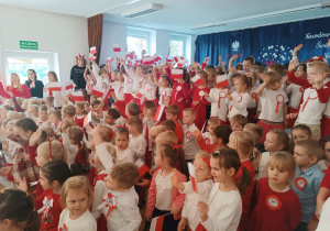 Dzieci ubrane na biało czerwowno śpiewają hymn
