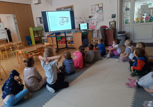 Dzieci oglądają prezentację multimedialną na temat historii roweru