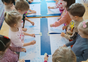 Dzieci robią kreski na przyklejonych kartkach.