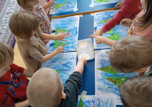 Dzieci stemplują palcem umoczonym w białej farbie.